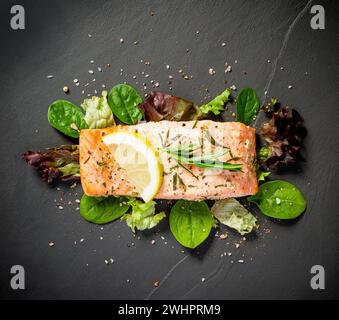 Gegrilltes Lachsfilet mit Salat auf schwarzem Schiefer Platte Stockfoto