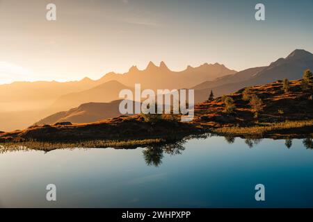 Malerische Landschaft mit goldenem Sonnenaufgang über dem Arves-Massiv mit einsamem Baumwechsel am Lac Guichard in den französischen Alpen, Frankreich Stockfoto
