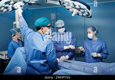 Gruppe der konzentrierten Chirurgen bei chirurgischer Operation im Operationssaal. Teamarbeit in der chirurgischen Abteilung Stockfoto