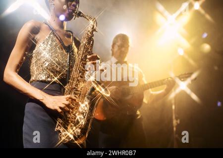 Nahaufnahme einer Jazz-Duo-Band, die während eines Live-Musikkonzerts auf der Bühne auftritt, mit einer jungen Frau, die im Vordergrund Saxophon spielt, im Kopierraum Stockfoto