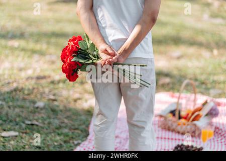Glückliches romantisches Paar am Valentinstag asiatischer Mann, der rote Rosenblume hinter sich versteckt, um seine Freundin zu überraschen. Stockfoto