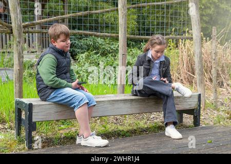 Teenager im Park mit Handys. Gadget-sucht. Der Junge hat das Telefon satt. Soziale Kommunikation. Stockfoto