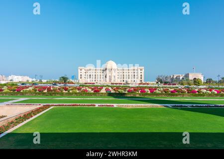 Vorderansicht am Obersten Gerichtshof von Oman in Maskat, Oman. Sonnige Tagesgärten im Vordergrund. Stockfoto