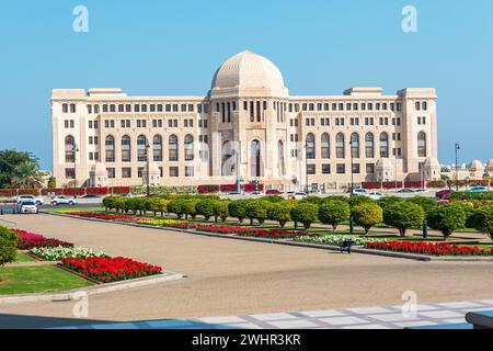 Vorderansicht am Obersten Gerichtshof von Oman in Maskat, Oman. Sonnige Tagesgärten im Vordergrund. Stockfoto