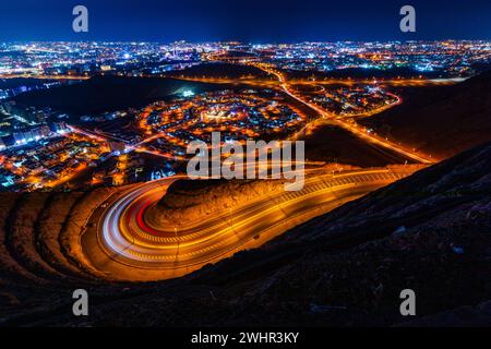 Blick vom Aussichtspunkt Amirat auf der wellenförmigen Straße in Muscat bei Nacht Stockfoto