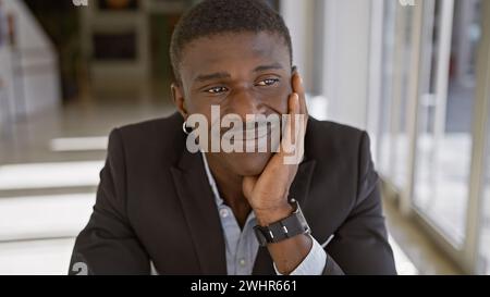 Porträt eines lächelnden afroamerikanischen Mannes, in Geschäftskleidung gekleidet, posiert in einem modernen Büroumfeld. Stockfoto