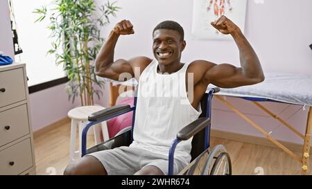 Schöner schwarzer Mann, der in einem Rollstuhl in einem Reha-Klinikraum selbstbewusst Muskeln beugt, steht für Kraft und Erholung. Stockfoto