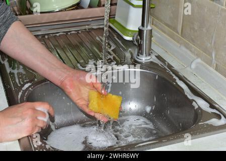 Auf dem Bild wäscht die Hand einer Frau unter fließendem Wasser einen Waschlappen über das Waschbecken. Stockfoto