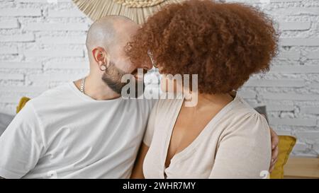 Ein nettes, selbstbewusstes Paar genießt einen lustigen Morgen zusammen, sitzt auf ihrem Bett, wacht mit Lächeln und Freude auf und sieht sich gegenseitig in ihrem wunderschönen Bett an Stockfoto