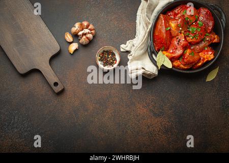 Kochen von Fleischeintopf. Rohe, nicht gekochte, gehackte Fleischstücke, mariniert mit Gewürzen und Petersilie in schwarzer Auflaufform, Blick von oben, c Stockfoto