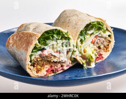 Köstliche frische Falafel-Wrap mit Gemüse und Sauce auf einer blauen Platte Stockfoto