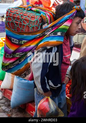 Chichicastenango, Guatemala.  Jungen tragen die Familie Einkäufe auf dem Markt. Stockfoto