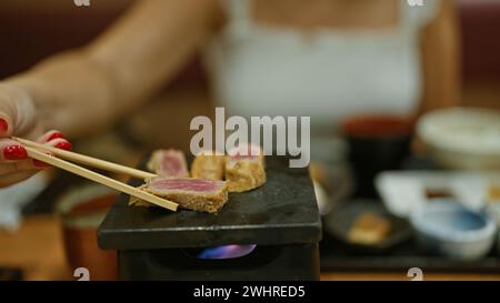 Porträt der brünetten hispanischen Frau im Restaurant, genießen ein Gourmet-Gyukatsu-Abendessen in einem modernen Café, Frau mit Gläsern und köstlichem japanischem k Stockfoto