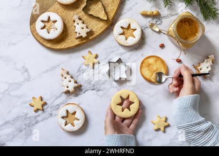 Hausgemachtes süßes Geschenk. Linzer Weihnachts- oder Neujahrsplätzchen gefüllt mit Erdnussbutter auf Marmorplatte. Draufsicht Flat Lay Backgr Stockfoto