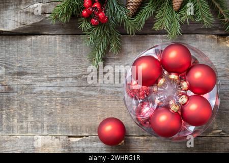 Postkartenmotiv im Vintage-Stil. Rote Weihnachtskugeln Dekorationen auf einem Holzhintergrund mit Kopierraum. Stockfoto