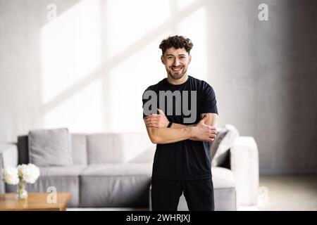 Athlet man trainiert hart in leerem Fitnessstudio oder zu Hause vor dem Laptop. Selbstisolierte und motivierte Aufwärmübungen für junge Männer Stockfoto