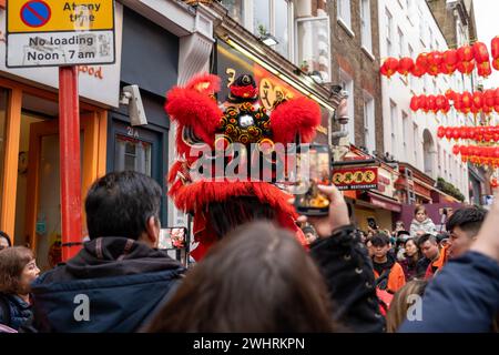 Menschenmassen versammeln sich um einen Drachentänzer in China Town, London. Tausende feiern das chinesische Neujahr, das Jahr des Drachen. Stockfoto