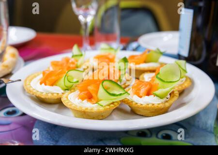 Törtchen mit Frischkäse, Räucherlachs und Gurke auf festlichem Teller Stockfoto