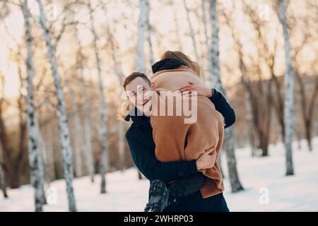 Liebevolles junges Paar, das im Winterwaldpark spielt und Spaß hat Stockfoto