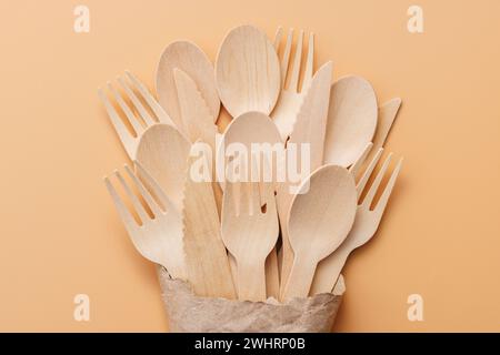 Biologisch abbaubare Holzlöffel und -Gabeln in einer Papiertüte auf beigefarbenem Hintergrund Stockfoto