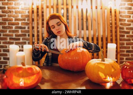 Junge Frau macht Halloween Kürbis Jack-o-Laterne. Weibliche Hände schneiden Kürbisse mit Messer. Stockfoto