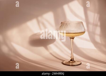 Glas mit Weißwein auf hellem Hintergrund mit Schatten Stockfoto