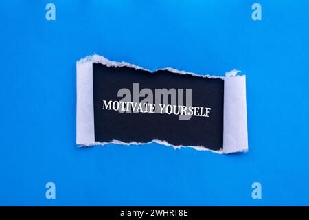 Motivieren Sie sich selbst mit Worten auf gerissenem blauem Papier mit schwarzem Hintergrund. Konzeptsymbol. Kopierbereich. Stockfoto