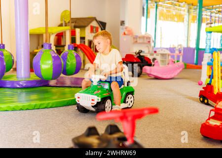 Junge, der auf dem Spielzeugauto auf dem Spielplatz sitzt Stockfoto