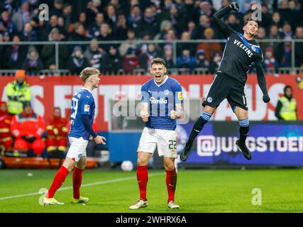 11. Februar 2024, Schleswig-Holstein, Kiel: Fußball, 2. Bundesliga, Holstein Kiel - FC Schalke 04, 21. Spieltag, Holsteinstadion. Kiels Nicolai Remberg (Mitte) feiert den Sieg neben Kiels Niklas Niehoff (links) beim Schlusspfeifen. Neben ihm springt Schalkes Yusuf Kabadayi in die Luft. Das Spiel endete 1:0. Foto: Axel Heimken/dpa - WICHTIGER HINWEIS: Gemäß den Vorschriften der DFL Deutschen Fußball-Liga und des DFB Deutschen Fußball-Bundes ist es verboten, im Stadion und/oder des Spiels aufgenommene Fotografien in Form von sequenziellen Bildern zu verwenden oder zu verwenden Stockfoto