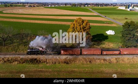 Seitenansicht eines Dampfzugs aus der Luft, der durch Ackerland fährt und Rauch bläst Stockfoto