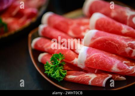 Geschnittenes Wagyu-Rindfleisch für Yakiniku auf Platte auf schwarzem Hintergrund, japanisches Premium-Fleischkonzept Stockfoto
