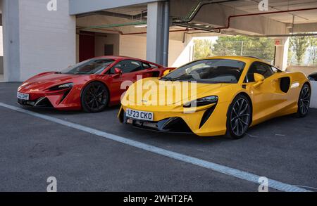 Vorderansicht eines Paares moderner McLaren Artura Supercars, einer rot und der andere gelb Stockfoto