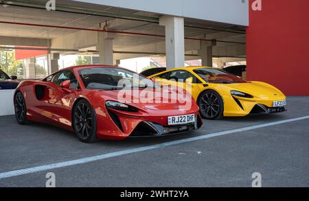 Vorderansicht eines Paares moderner McLaren Artura Supercars, einer rot und der andere gelb Stockfoto