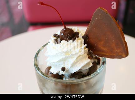 Großaufnahme von Maraschino-Kirsche mit Schokoladenbeschichtung und Eiscreme Sundae Schlagsahne Stockfoto