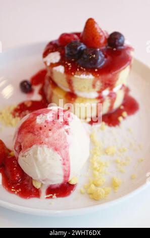 Vanilleeis und Chiffonkuchen mit Erdbeeren- und Heidelbeersauce Stockfoto