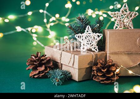 Nachhaltige Weihnachtsgeschenkboxen mit natürlichem Dekor und glänzender Girlande auf grünem Hintergrund. Weihnachten Null Verschwendung Stockfoto