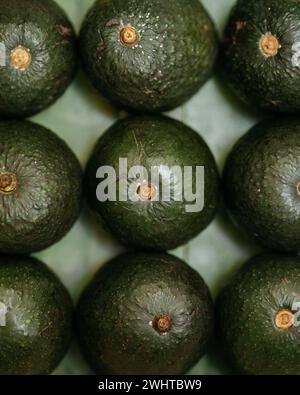 Nahaufnahme frischer Avocados, die ordentlich auf einer strukturierten Oberfläche angeordnet sind Stockfoto