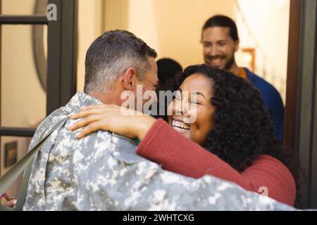 Fröhliche Freunde mit Fahnen, die männlichen Soldatenfreund willkommen heißen Stockfoto