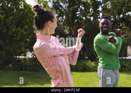 Glückliches, vielseitiges Paar, das Yoga und Dehnen im Garten praktiziert Stockfoto