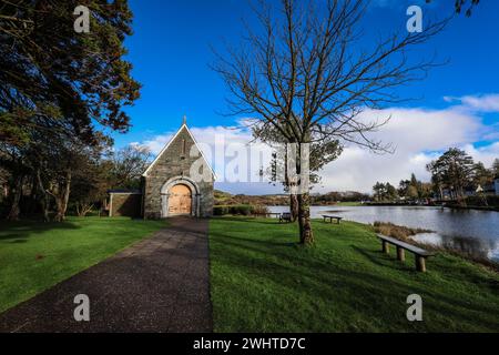 Zeitlose Ruhe in Gougane Barra, County Cork, Irland – wo das Wasser anmutig um eine historische Kapelle fließt und die Essenz der Ruhe einfängt Stockfoto