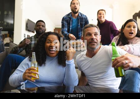 Begeisterte verschiedene männliche und weibliche Freunde, die zu Hause Sport im fernsehen sehen und Bier trinken, Kopierraum Stockfoto