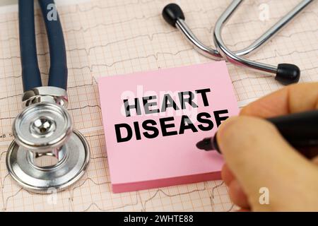 Medizinisches Konzept. Auf den Kardiogrammen gibt es ein Stethoskop und einen Aufkleber mit der Aufschrift - Herzkrankheit Stockfoto