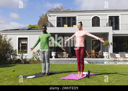 Verschiedene Paare üben Yoga und dehnen sich im Garten Stockfoto