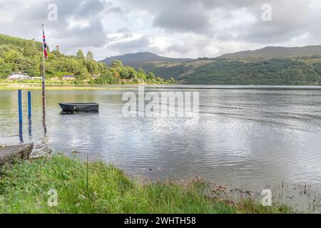 Die Flagge der Union Jack an einem Stange mit einem Boot, das bei Flut im See Loch Sunart in Strontian, Highlands, Schottland gefesselt ist Stockfoto