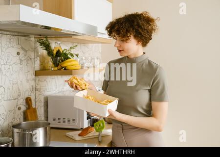 Junge Frau, die Pappardelle-Pasta in den Händen hält, über den Topf mit kochendem Wasser Stockfoto