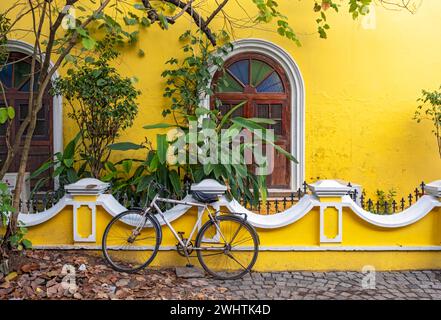 Straßenszene mit Fahrrad vor dem gelben Haus, Fort Kochi, Cochin, Kerala, Indien Stockfoto