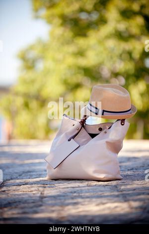 Weibliche Ledertasche und Textilmütze auf Straßenbelag Stockfoto