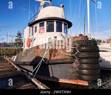 Ein alter rostiger Schlepper mit einem Schild zum Verkauf im Fenster. Gefesselt an einem Dock Stockfoto