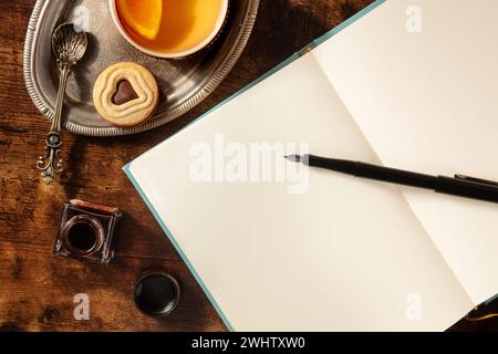 Tagebuch-Mockup mit Orangentee und Schokoladenkeks, mit Tinte und einem Stift Stockfoto