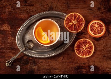 Orangentee mit frischen und getrockneten Orangen auf einem Vintage-Tablett auf einem Holztisch Stockfoto